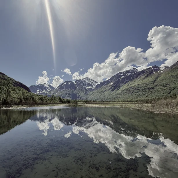 Snow-streaked mountains and cloud reflected in a perfectly still lake